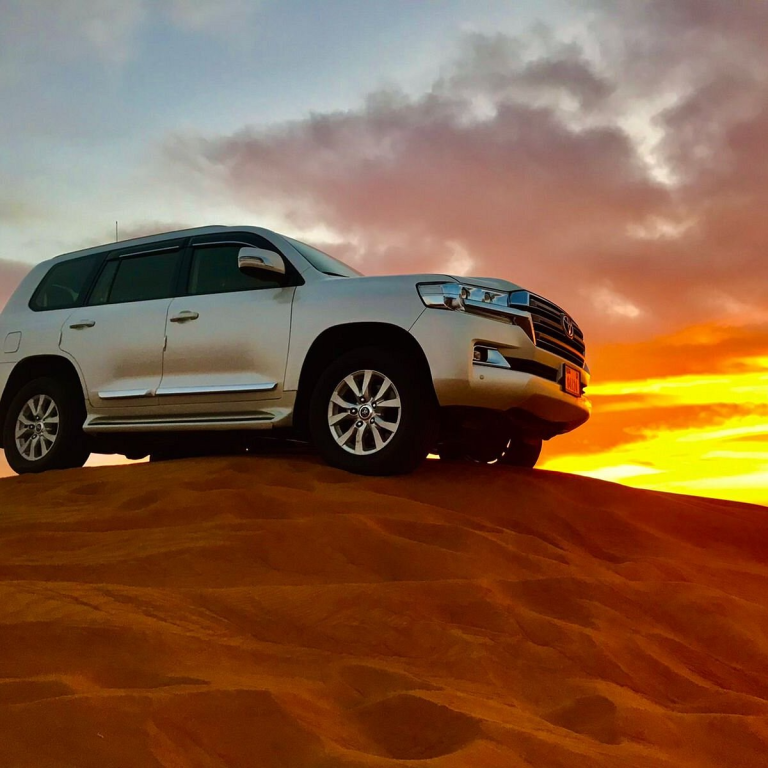 car on a dune during sunset